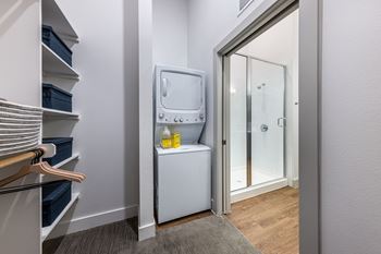 A small laundry room with a washer and dryer in it and a mirror